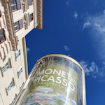 Column advertising an exhibition, building and blue sky